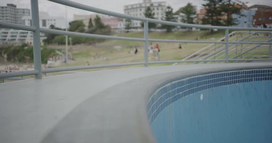 Young man skates inside empty pool in city at day
