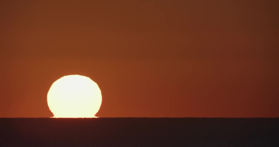 Sun rises over the horizon turning the sky and landscape orange and brown