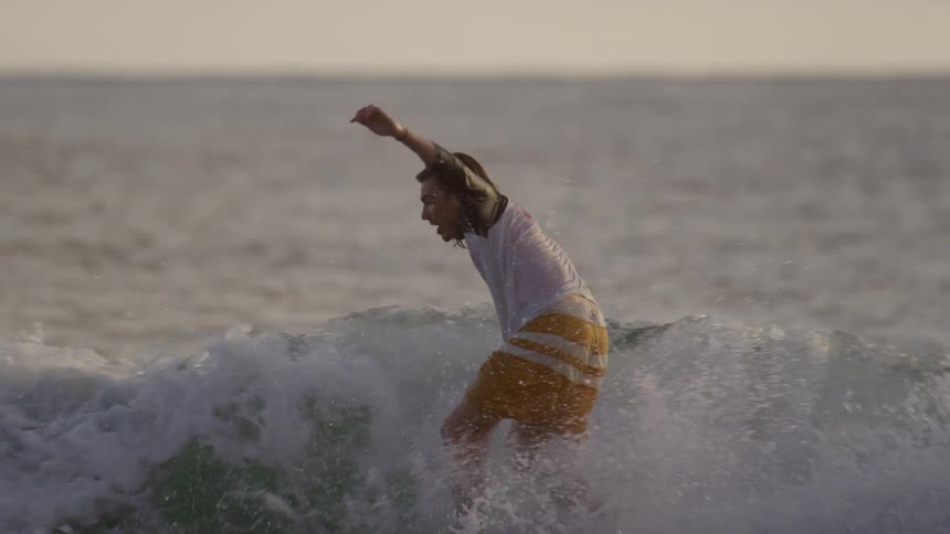 A surfer stands on his board and rides a wave