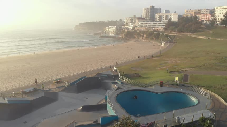 Aerial view of people doing leisure activities next to the golden beach at sunset