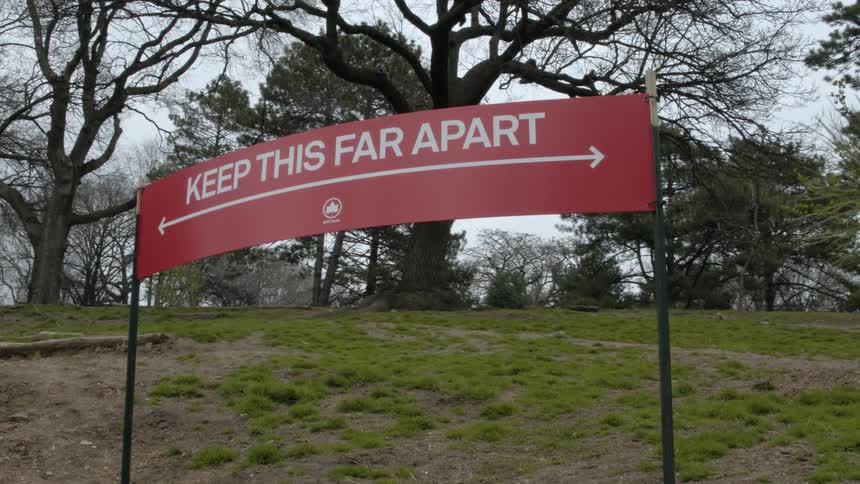 A sign in a park tells people to keep distance between each other