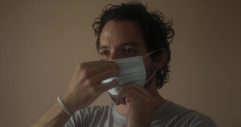 Man with beard and mustache puts on and adjusts face mask