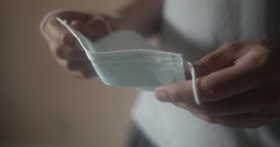 A woman holds a disposable face mask in her hands
