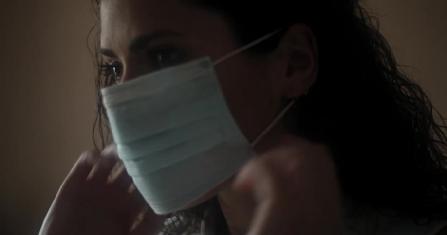 A woman places a disposable mask on her face covering her nose and mouth and adjusts it
