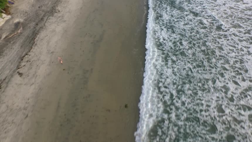Waves come to shore as people run on the beach