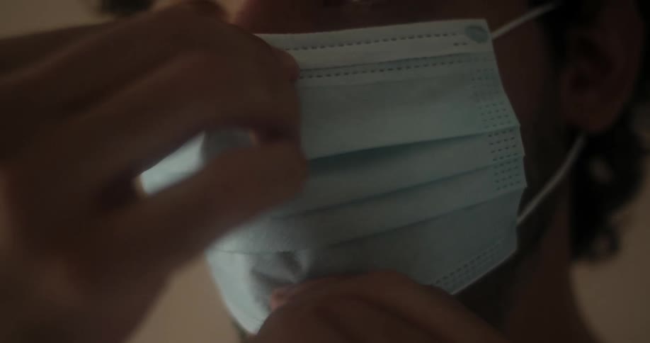A young man puts a mask on his face