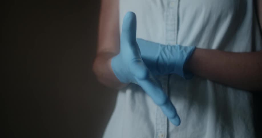 A woman in a sleeveless shirt puts on blue latex gloves