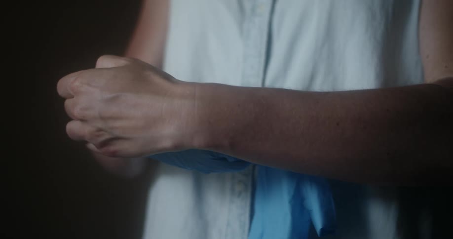 A person taking off a pair of blue disposable gloves