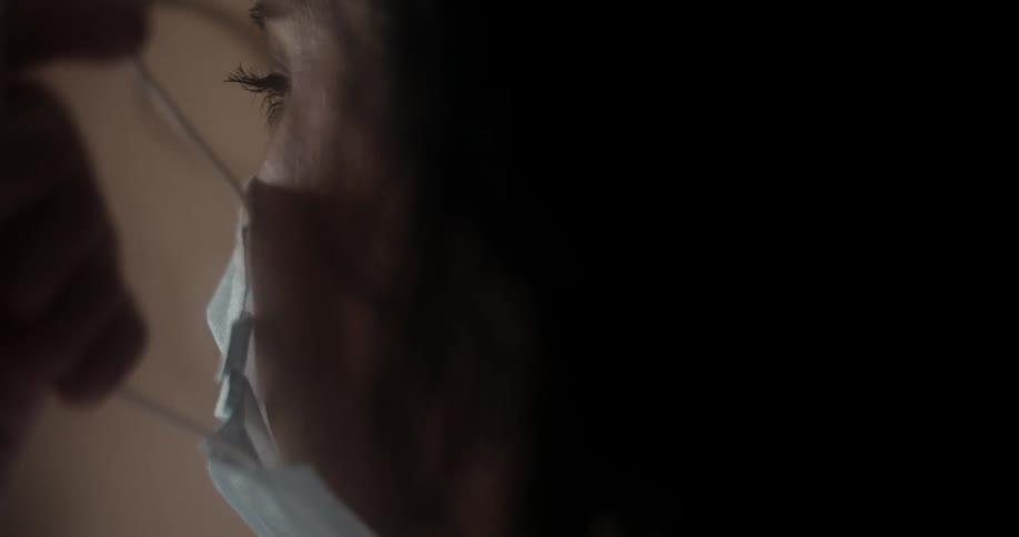 A woman removing a medical face mask from her face