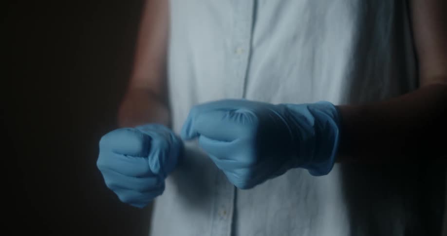 Person pulls blue latex gloves further up their arms