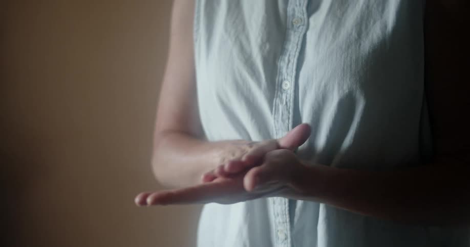 A woman spraying hand sanitizer on her hands then rubbing it in