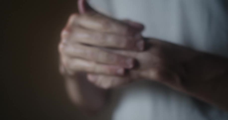 A person spraying a bottle of hand sanitizer on their hands then rubbing it in
