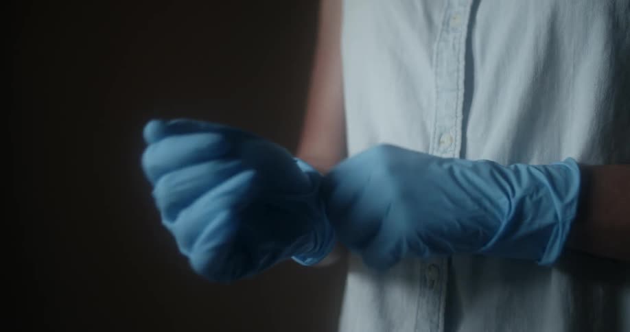 A person adjusting blue latex gloves on their hands