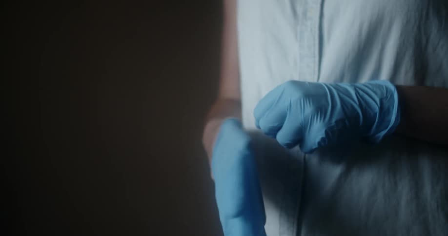 A person putting on a pair of latex gloves