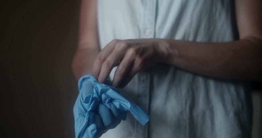 A person taking off a pair of blue disposable gloves