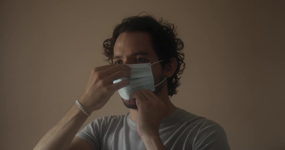 A man demonstrates how to put on a face mask and walks away