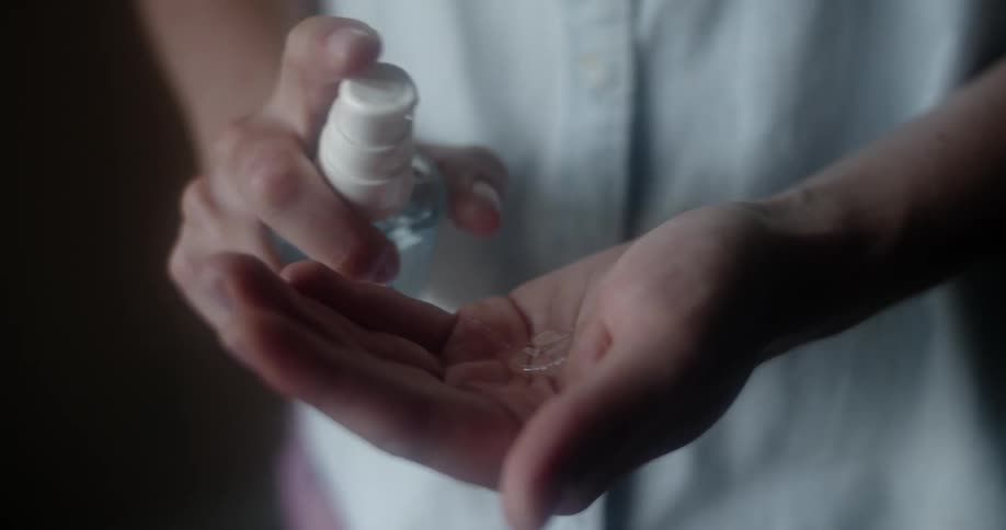 A woman squirts sanitizer in her hands and rubs her hands together