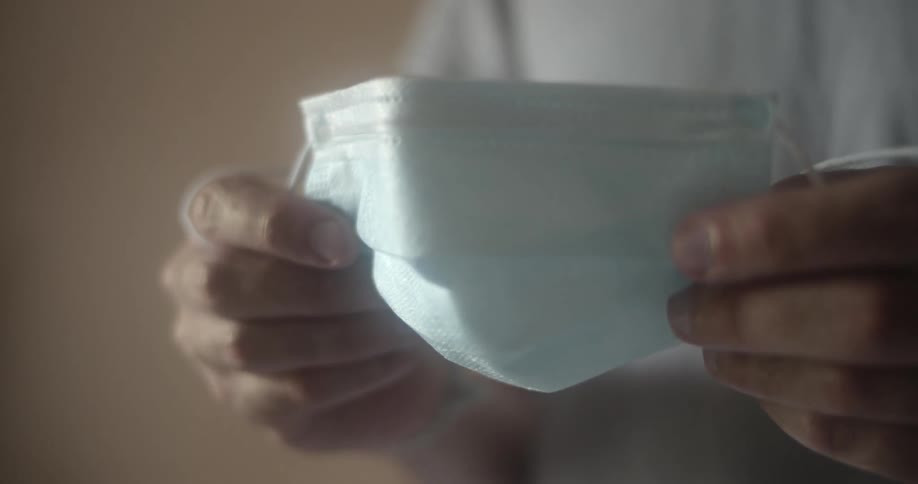 Person holds face mask by its sides