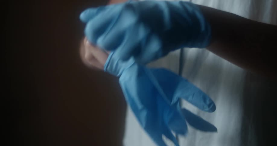 A person putting on blue latex gloves