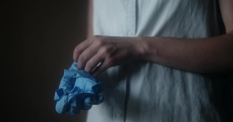 A woman removes blue latex gloves from her hands