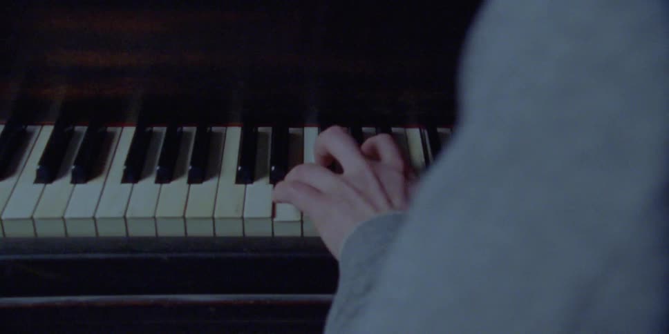 A pianist playing a piano in a dimly lit room