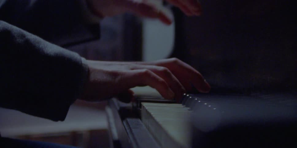 Man wearing a suit with a long sleeve shirt play the piano