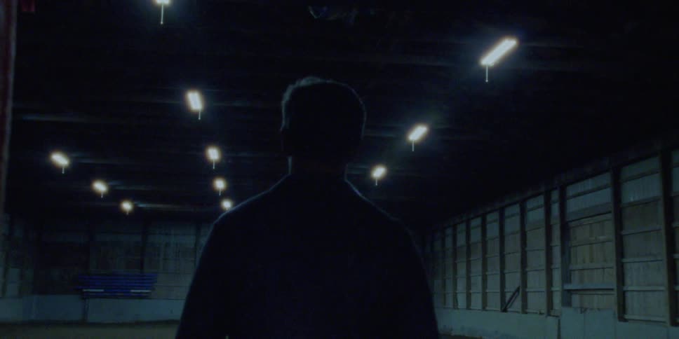A man walks down a hallway and into a large open hangar