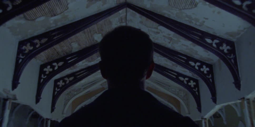 A man stands in the hallway of a deserted building