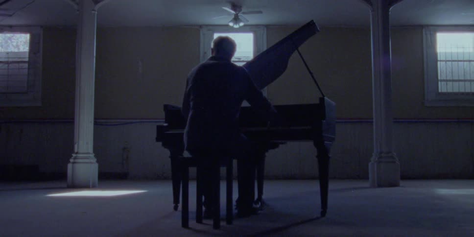 A person plays a piano in a dark room
