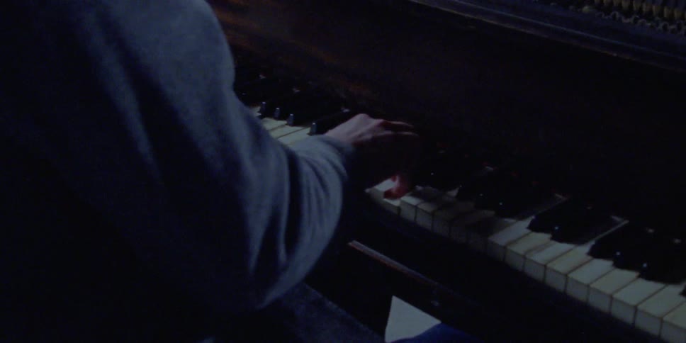 Person wearing long sleeve shirt plays piano