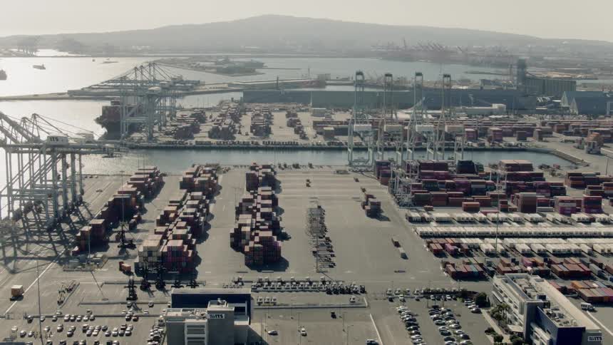 An aerial view of a parking lot by the ocean coast is displayed