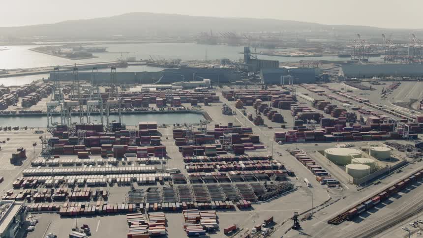 A shipping yard next to the water is filled with cargo containers