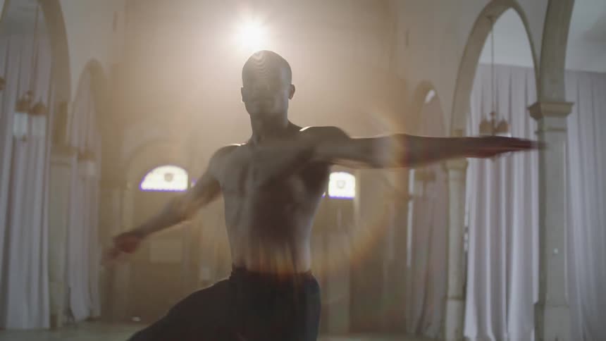 A man in a building with arch doorways spinning and dancing