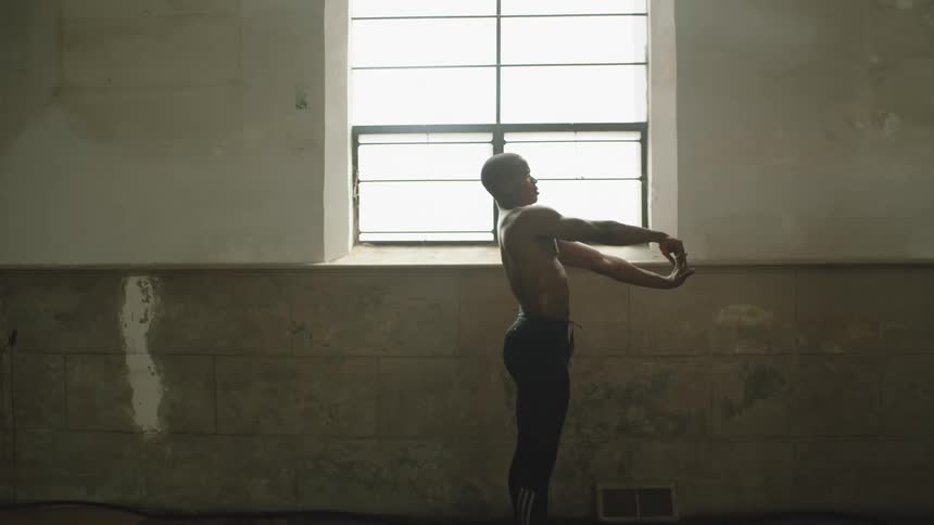 Shirtless black man warms up before dancing in a room