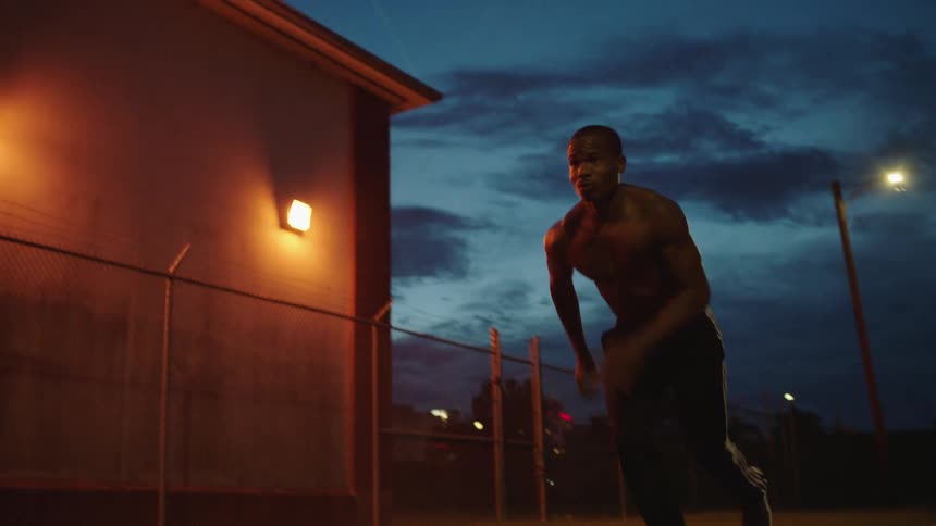 Shirtless black man starts running outdoors at dusk