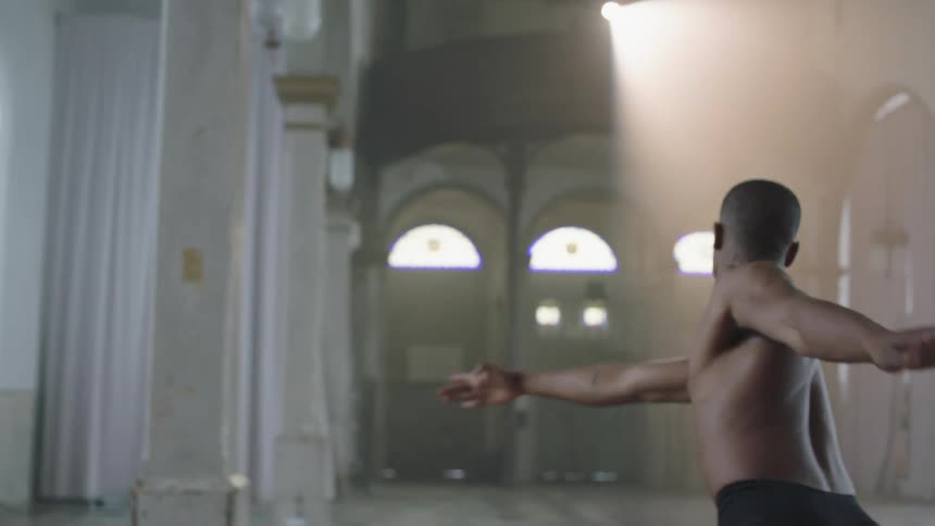 A male ballet dancer practices in a large open ornate room