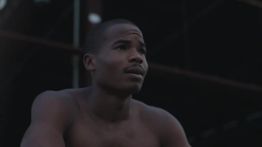 A shirtless man takes a breather and rests with his head on his arms