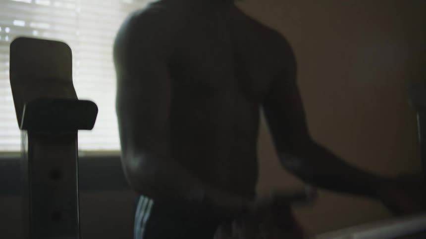 Personal trainer helps man lift a barbell