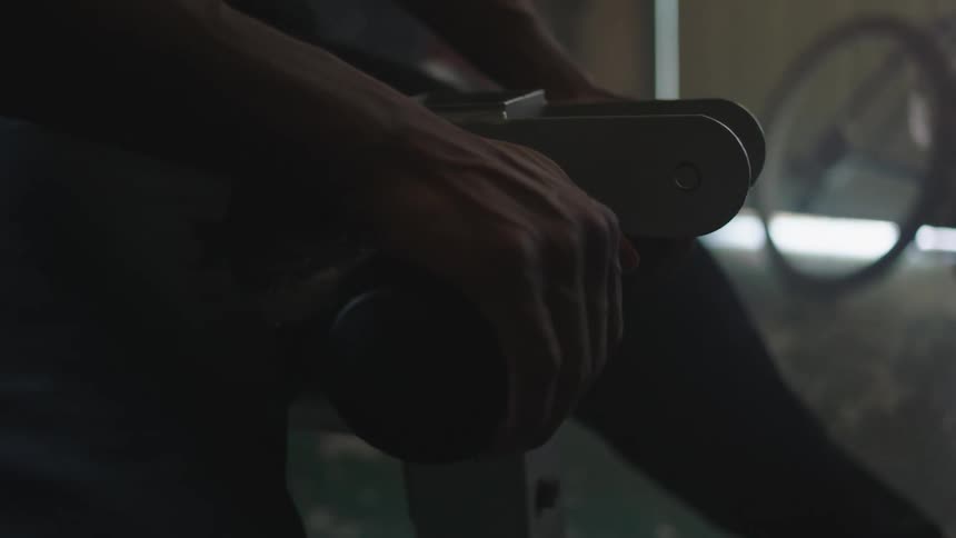 A mans hand gripping a bar on a weight bench tenses