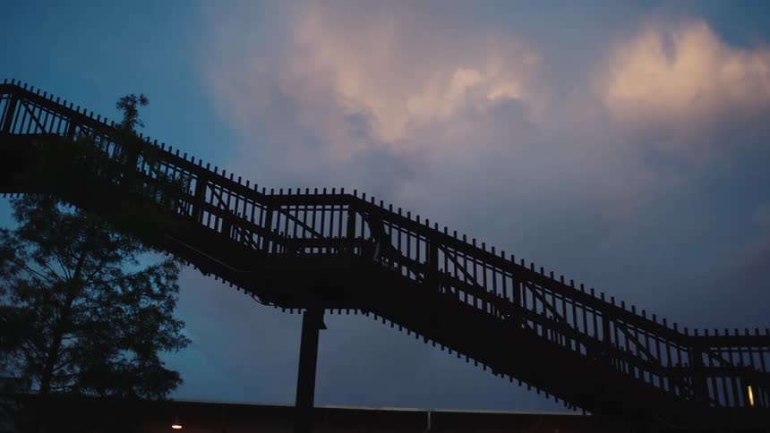 A man runs up a staircase outdoors at sunrise
