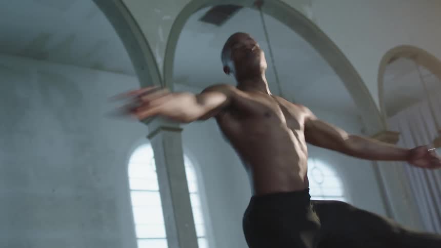 A man twirling and dancing in a room with arched doorways and windows