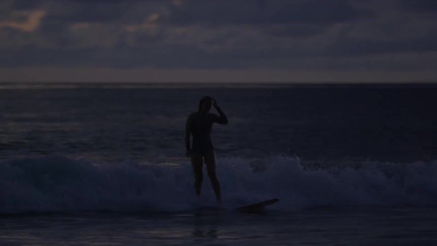 A surfer is surfing at dusk