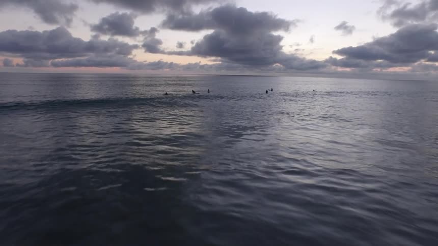 People are surfing in the water at sunset