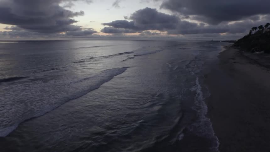Straight lines of waves hit the beach