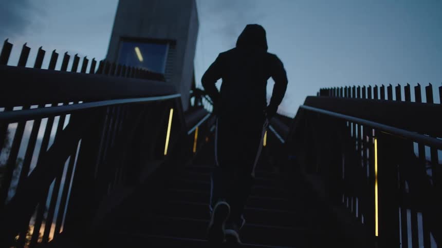 Person jogs up staircase toward sky with pink tinged clouds
