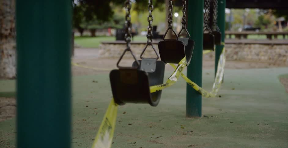 Closed playground swings wrapped in caution tape