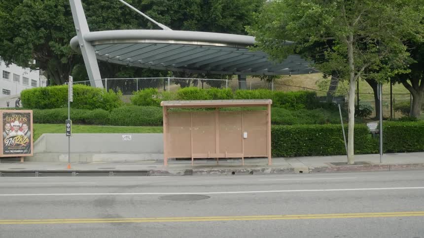 A bus travels past an empty bus stop on a city street