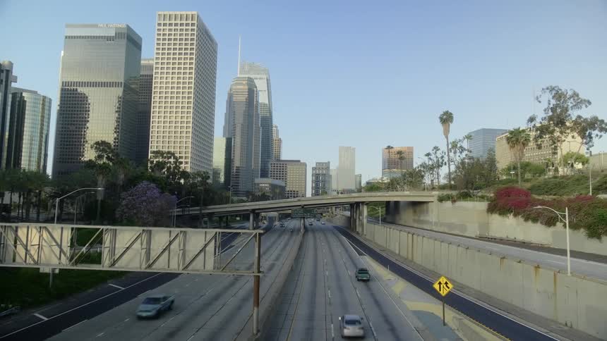 A highway with vehicles with buildings and skyscrapers in the background