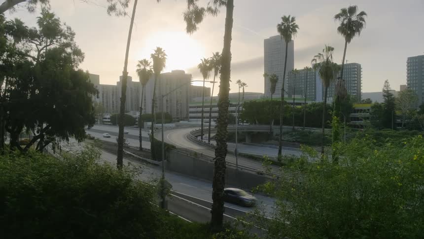 Cars are driving on a highway near a skyline at dusk