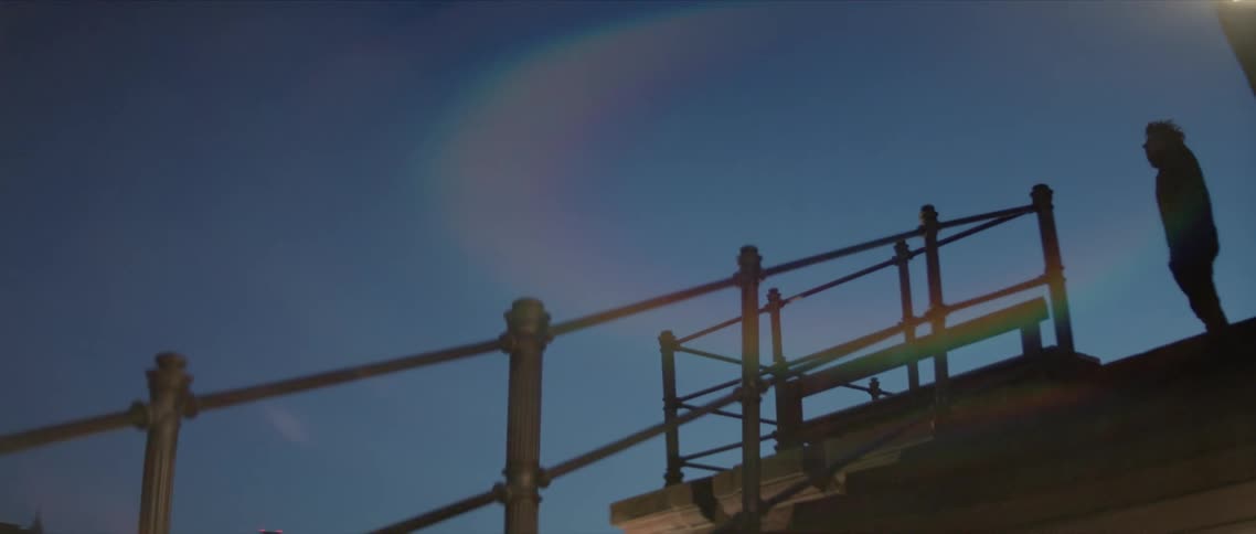 A man stands at the top of some stairs and looks around